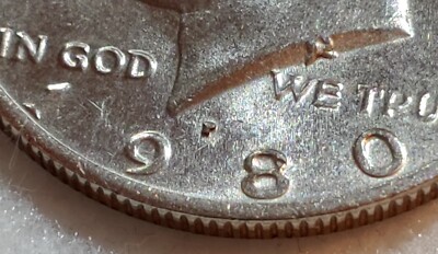 Close-up of 1980-P half dollar showing filled or blobby P mint mark error compared to normal sharp P